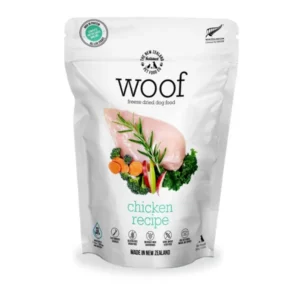 A white pouch of Woof freeze-dried dog food, chicken recipe flavor, featuring an image of raw chicken breast with rosemary, carrots, and greens on the front. The packaging indicates it is made in New Zealand and is gluten free.