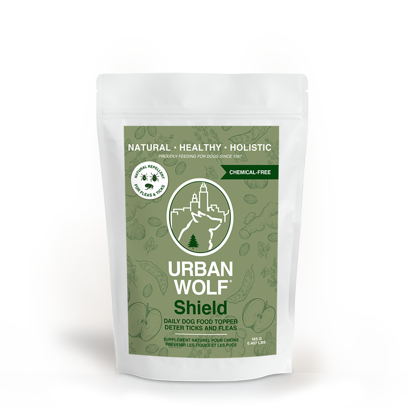 A white pouch labeled "Urban Wolf Shield" daily dog food topper, with green packaging highlighting it is natural, healthy, holistic, and chemical-free; designed to deter ticks and fleas.