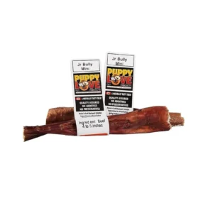 Two packages of Puppy Love Jr Bully Mini dog treats are displayed with a single long treat lying in front. The packaging highlights natural ingredients, quality assurance, and lack of preservatives.