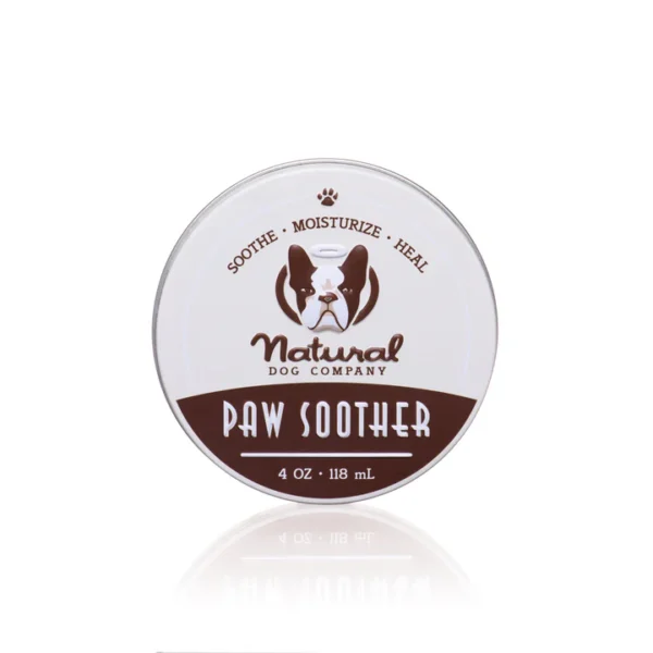 A round tin container labeled "Natural Dog Company Paw Soother." The design includes an image of a dog's face and text indicating the product's purpose: "Soothe • Moisturize • Heal." The container holds 4 oz (118 ml) of product.