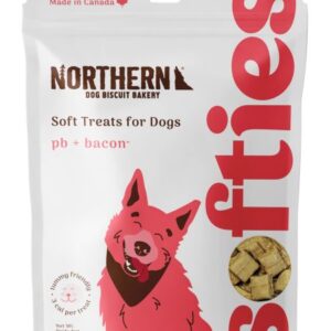 A 170 g bag of Northern Soft Treat for Dogs Peanut Butter & Bacon features a white package with a pink smiling dog illustration and a window showing square treats inside. Made in Canada.