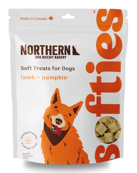 A package of Northern Dog Biscuit Bakery treats labeled "Soft Treats for Dogs" with lamb and pumpkin flavor. The package is white with orange text and features an illustration of a happy dog. The net weight is 170 grams and it's made in Canada.