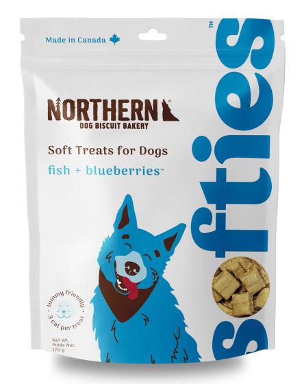 Bag of Northern Dog Biscuit Bakery soft treats for dogs, featuring fish and blueberries flavor. The packaging includes an illustration of a blue dog and a Canadian flag symbol.