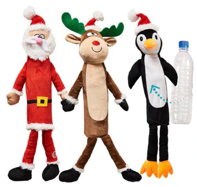 Three plush toys—a Santa, a reindeer, and a penguin—all wearing Santa hats, are shown standing next to a plastic bottle for size comparison. Each toy has long, floppy arms and legs.