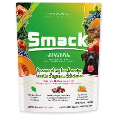 A bag of Smack brand raw dehydrated superfood for dogs, featuring a lamb recipe. The package is green and shows images of fresh fruits, vegetables, and a black dog. Various product benefits and details are printed on the bag.
