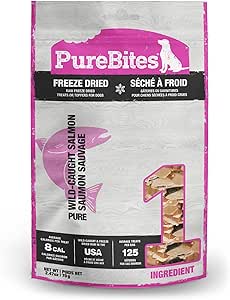 Bag of PureBites freeze-dried dog treats, wild-caught salmon flavor. The packaging is mostly white and pink, showing images of salmon and the treats, with product details and nutritional info on the front.
