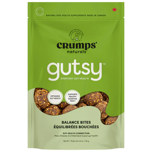 A green resealable bag of Crumps' Naturals Gutsy Balance Bites dog treats, featuring images of the treats and text highlighting gut health benefits. The package is labeled as made in Canada.