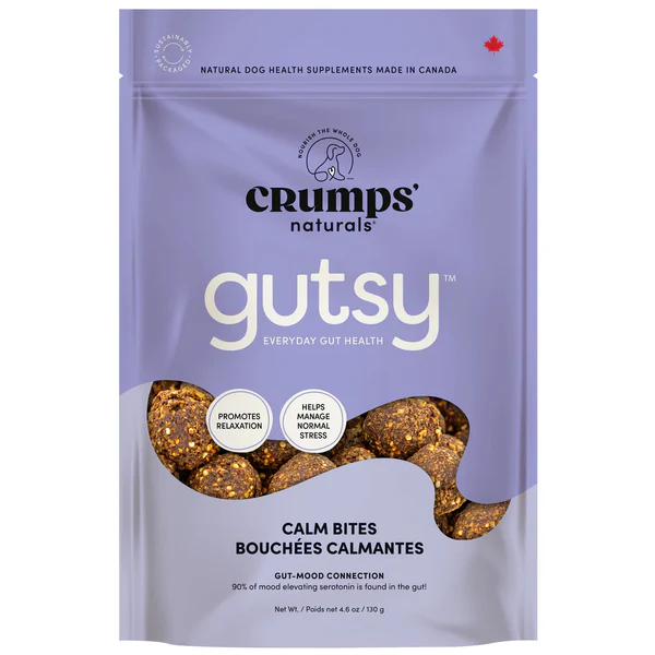 A purple resealable bag of Crumps' Naturals Gutsy Calm Bites dog treats. The packaging highlights gut health benefits, mood support, and relaxation, with images of round treats and text indicating it's made in Canada.