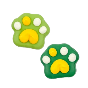 Two decorated cookies shaped like animal paw prints, one light green and the other dark green, both with yellow pads and white toes, on a transparent background.