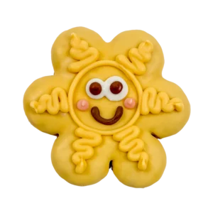 A yellow, flower-shaped cookie decorated with a smiling face, large white eyes, pink cheeks, and swirly yellow icing on each petal.