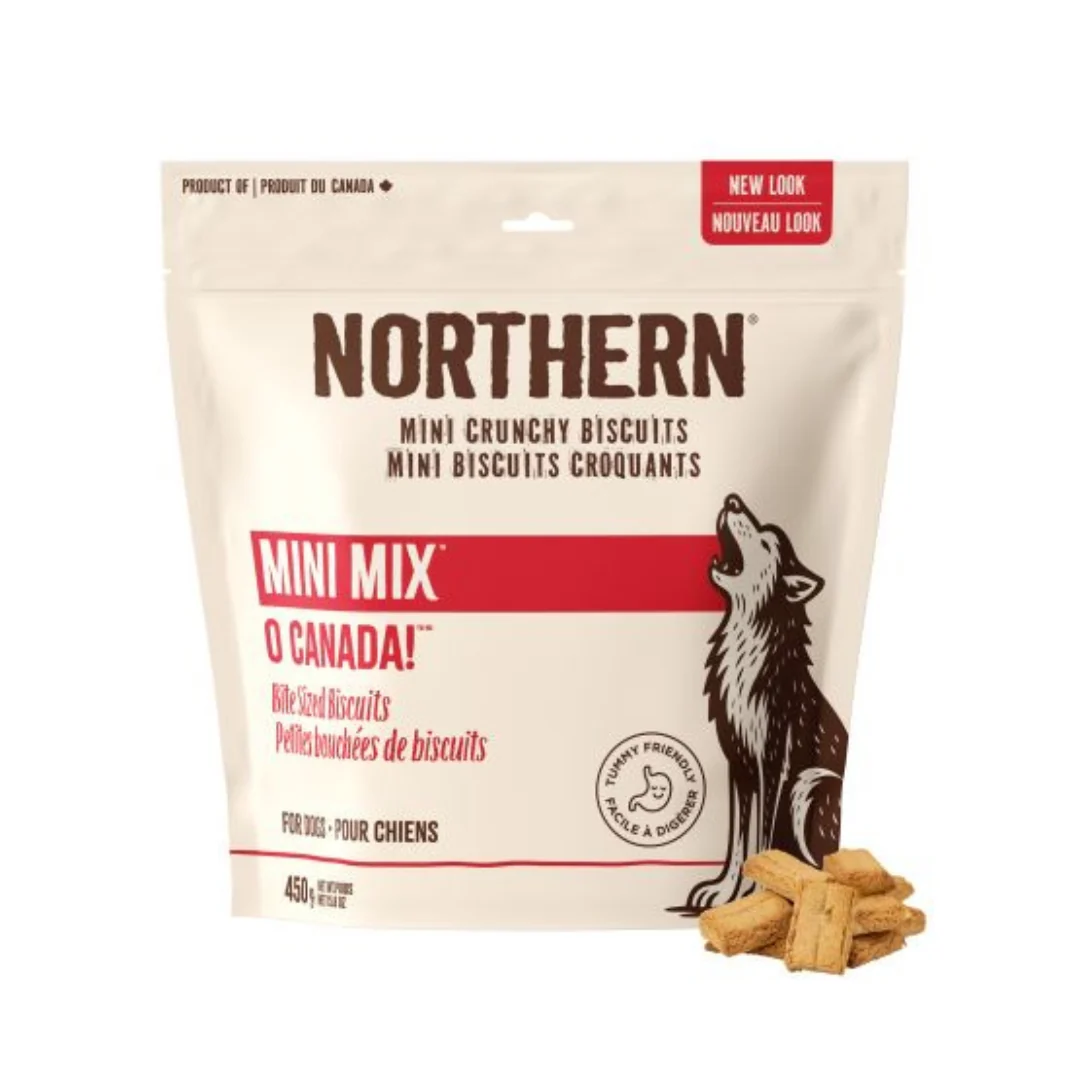 A 450 g bag of Northern MiniMix Oh Canada dog biscuits, featuring a howling wolf graphic with several mini crunchy biscuits shown in front. The packaging is beige and red.