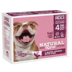 A box of Natural Raw Foods dog food is shown. The packaging features a happy bulldog with its mouth open. The product is labeled as "3 Blend Dinner with Fish," indicating four 1 lb meals. The packaging claims "100% meat & salmon" and is high in protein.