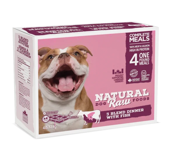 A box of Natural Raw Foods dog food is shown. The packaging features a happy bulldog with its mouth open. The product is labeled as "3 Blend Dinner with Fish," indicating four 1 lb meals. The packaging claims "100% meat & salmon" and is high in protein.