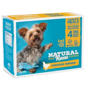 A box of "Natural Raw Foods" dog food featuring a small, happy dog. The product is labeled as "Chicken Dinner" and contains 100% chicken. The package includes four 1-pound meals and weighs 4 lbs (1.8 kg). The text highlights its high protein content.