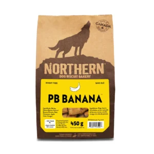 A brown paper bag of Northern Dog Biscuit Bakery PB Banana dog treats, featuring a wolf silhouette, the weight (450g), and a yellow label listing ingredients and stating it's wheat-free.