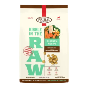 A bag of Primal Pet Foods featuring "Kibble in the Raw" chicken recipe. The packaging shows illustrations of chicken, carrots, squash, and kale. Notable text highlights "kibble-sized bites" and "freeze-dried raw chicken.