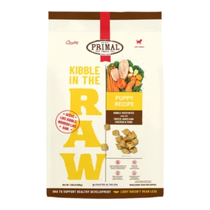 A package of Primal Pet Foods "Kibble in the Raw" puppy recipe. Features kibble-sized bites with freeze-dried raw chicken and pork. The packaging includes images of chicken, vegetables, and small kibble pieces.