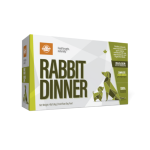 A box of "Rabbit Dinner" fresh raw dog food featuring green geometric animal designs and bold text. The packaging highlights natural ingredients and balanced nutrition.