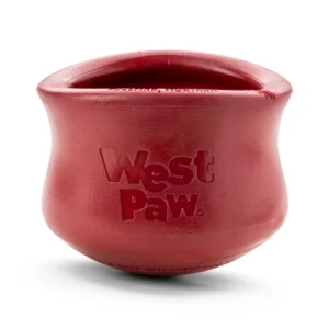 A red West Paw dog toy with a rounded, pot-like shape. The surface is smooth, and the brand name is embossed on the front.