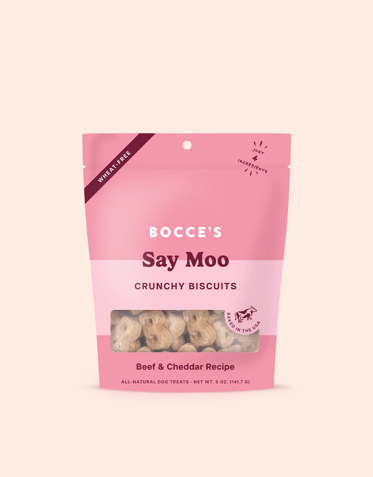 A pink and light pink resealable bag of Bocce’s Say Moo crunchy biscuits for dogs, labeled as wheat-free and made with beef and cheddar. The biscuits are visible through a clear window at the bottom.