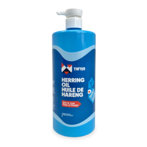 A blue 1L bottle of Thrive Herring Oil with a white pump dispenser. The bilingual label highlights “Skin & Coat” benefits and shows it's Thrive Herring Oil for pets.