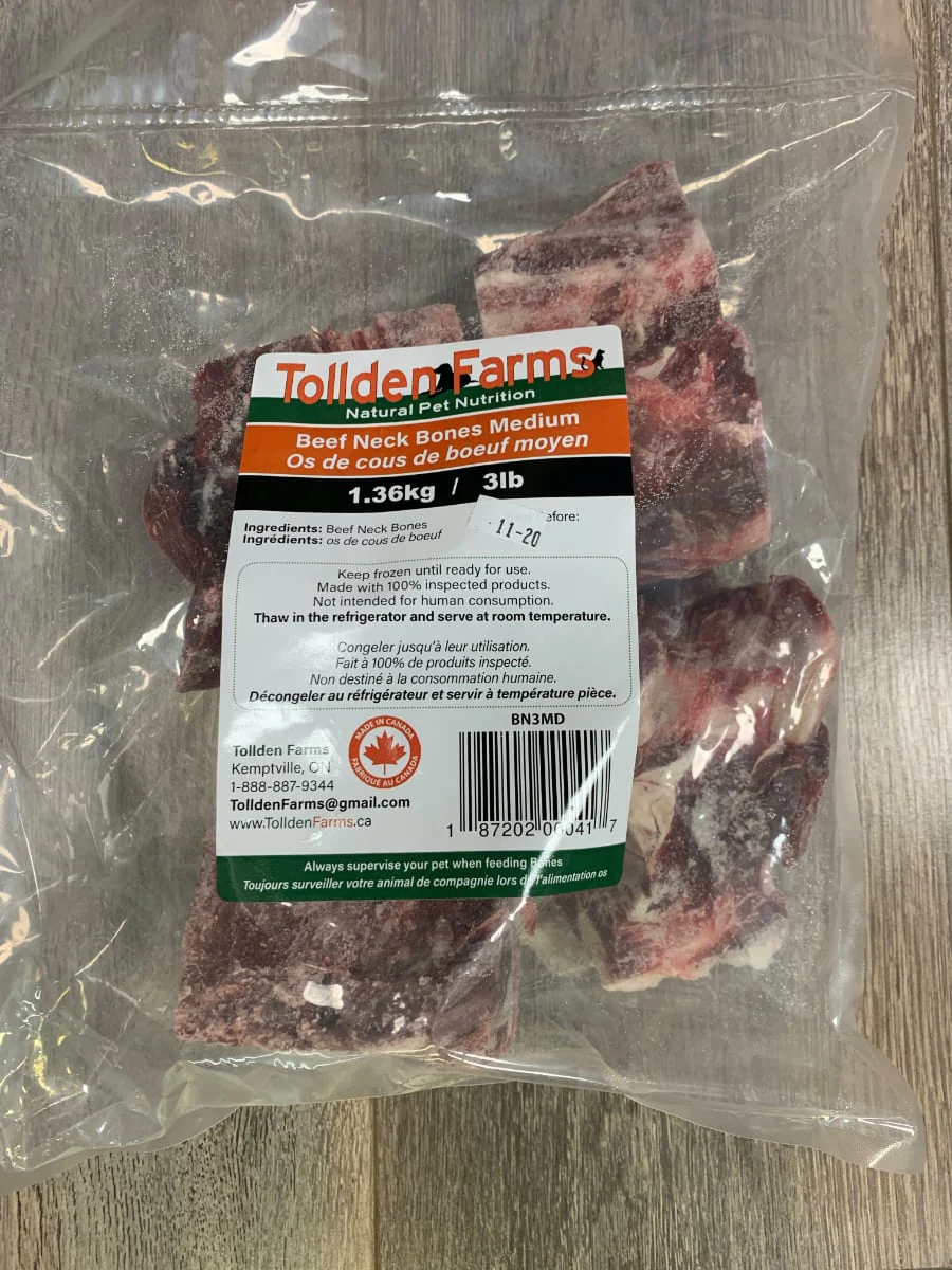 A vacuum-sealed bag of Tollden Farms Beef Neck Large 3 lbs rests on a wooden surface, featuring a label with product details and a Canadian maple leaf logo.