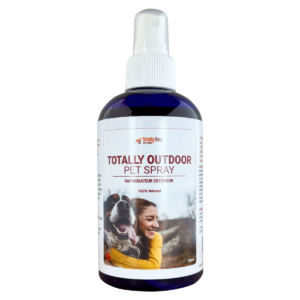 A bottle of Totally Outdoor Pet Spray with a spray nozzle. The label shows a woman hugging a happy dog outdoors and states that the product is 100% natural.