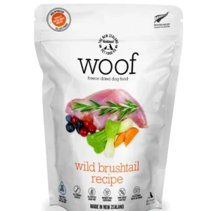 A package of Woof freeze-dried dog food, wild brushtail recipe. The front displays an image of meat, rosemary, blackberries, cranberries, carrots, and pumpkin. It is labeled "Made in New Zealand" and includes authenticity badges.