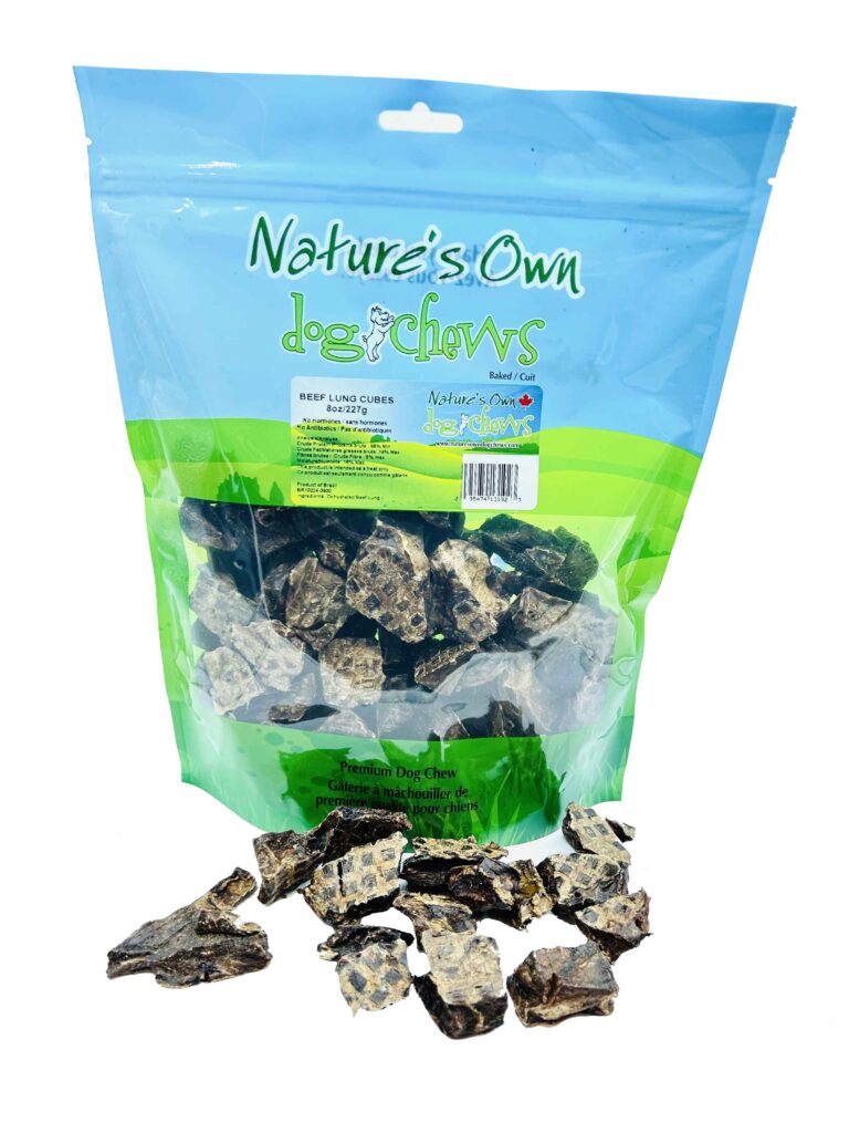 A blue and green resealable bag labeled “Nature’s Own Dog Chews” contains dried beef lung cubes, with several pieces scattered in front of the bag. The treats are brown and white in color.