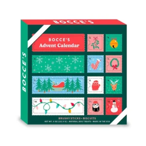 Advent calendar box for dogs by Bocce's, featuring 12 numbered compartments with festive designs like snowflakes, mittens, a fox, and a penguin. The box is green with red accents and contains brushy sticks and biscuits.