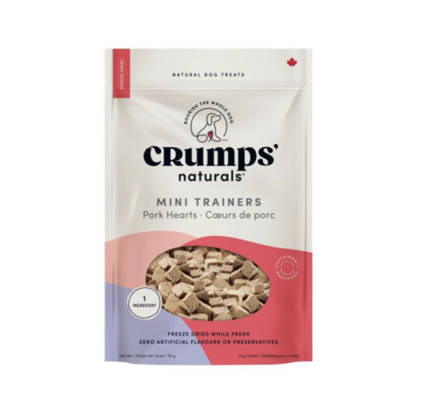 A bag of Crumps' Naturals Mini Trainers dog treats, pork hearts flavor. The packaging is white and pink with images of the treats, and text stating "freeze dried, 1 ingredient, no artificial flavors.