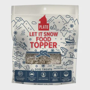 The image shows a package of dog treats labeled "Plato Let It Snow Food Topper." The packaging has illustrations of mountains, trees, and snowflakes. It highlights features like being 100% natural and rich in Omega 3.