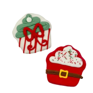 Two festive Christmas cookies: one shaped like a tree with green icing and red decorations, and another shaped like Santa's suit with red icing, a black belt, and white frosting topped with green and red sprinkles.