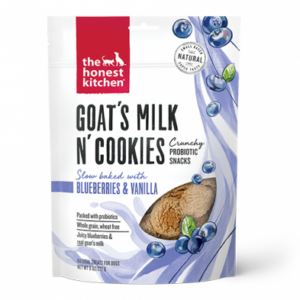 A white and purple bag of "The Honest Kitchen Goat's Milk N' Cookies" dog treats featuring blueberries and vanilla. The packaging highlights these snacks as probiotic, slow-baked, whole grain, and wheat-free. Blueberry images decorate the bag.