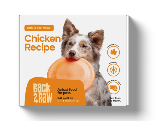 A package of Back2Raw Chicken Recipe pet food features a dog holding an orange frisbee in its mouth. The box highlights it is a complete meal, 5.44 kg, and intended to be kept frozen.