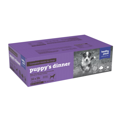 A purple box of Healthy Paws "puppy's dinner" complete meals for dogs, containing 16 one-pound packages. The packaging features a photo of a puppy sitting on grass. The box emphasizes high-quality ingredients, natural preservation, and product details.