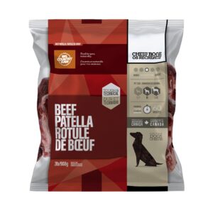 A package of Big Country Raw Beef Patella Bone 2 lbs, labeled in English and French, displays the bones through a clear window and features icons indicating it is 100% Canadian, suitable for dogs, and weighs 2lb/908g.
