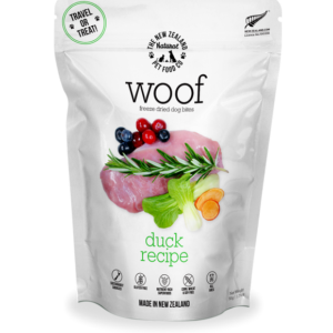 A white pouch of Woof Freeze Dried Dog Bites Duck 50g, displaying images of raw duck, herbs, and berries on the front; labeled as made in New Zealand and ideal for travel or treats.