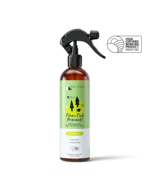 A brown bottle with a black spray nozzle labeled "Kin + Kind Outdoor Shield Spray For Dog & Cat 12 oz Lemongrass," featuring a green label adorned with trees and a dog silhouette. The text emphasizes natural ingredients and a lemongrass scent. A USDA Certified Biobased Product seal is prominently displayed, ensuring its quality.