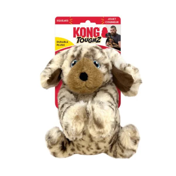 A plush dog toy with brown and white fur, floppy ears, and blue eyes. It is part of the KONG Toughz series, labeled as a durable squeaky toy. The packaging features the words "squeaks" and "durable plush.