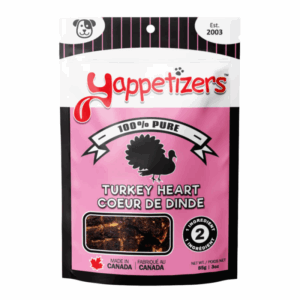 A pink and white bag of Yappetizers Turkey Heart 100g dog treats features a turkey silhouette, "Made in Canada" and "2 ingredients" labels, plus a clear window displaying the treats inside.