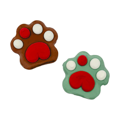 Two paw-shaped cookies are decorated with icing. One is brown with white toes and a red paw pad, while the other is green with similar decoration. Both have a playful, cartoon-like appearance.