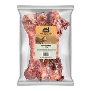 A transparent bag holds two large frozen bones labeled โRaw Performance Pork Femurs 2 Pack,โ with imagery of a pig and dog on the front. These Raw Performance Pork Femurs are premium treats intended as pet food, providing a flavorful, natural chew for your dog.