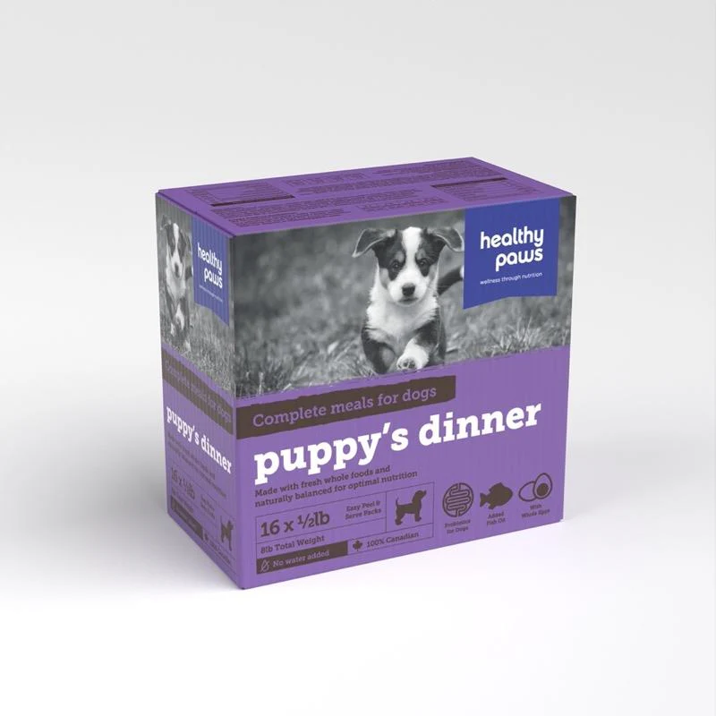A purple and white box labeled "puppy's dinner" from Healthy Paws, featuring a black and white photo of a puppy. The box advertises complete meals for dogs and contains 16 half-pound packs.