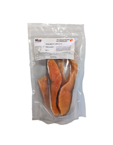 A sealed plastic package containing several raw salmon fillets with a white label on top showing product information.